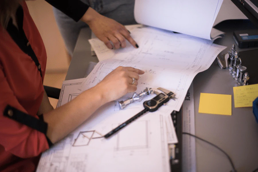 Hands reviewing an engineering drawing on a desk