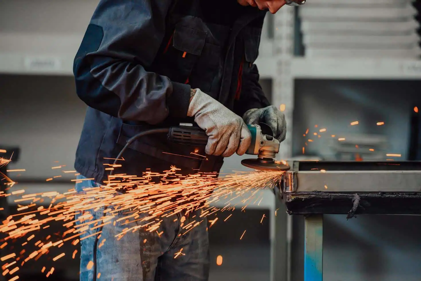 A worker grinding a metal surface with a handheld tool